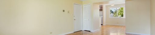 an empty living room with wood floors and white walls