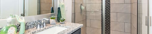 A bathroom with a sink, mirror, and shower.