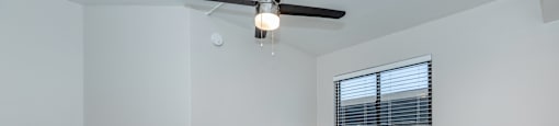 an empty living room with a ceiling fan and a window