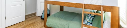 A bedroom with a bed, pillows, and a backpack.