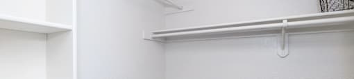 A white closet with shelves and a light on the ceiling.