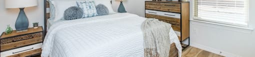 A bedroom with a bed, nightstands, and two framed artworks on the wall.