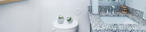 A bathroom with a toilet, a sink, and two pictures on the wall.