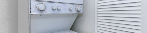 A white oven with a white door and white controls is next to a white wall with horizontal lines.
