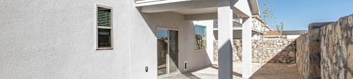A modern house with a white exterior and a stone wall.