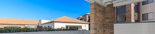 A white fence with a brick pillar in front of a garage.