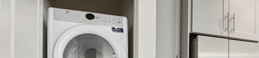 A white washing machine and dryer stacked on top of each other in a laundry room.
