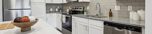 A modern kitchen with white cabinets and stainless steel appliances.