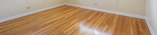 an empty room with two windows and wood floors
