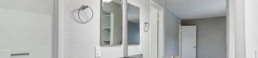 A bathroom with a sink, mirror, and lighting fixture.