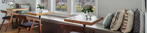 A room with a table and chairs by a window.