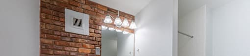 a bathroom with a brick wall and a toilet and a sink