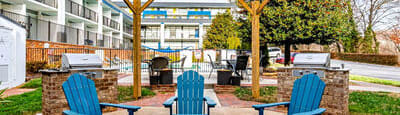 a patio with blue chairs and a fire pit