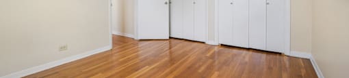 an empty room with wood floors and white closets