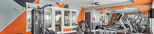 A gym with orange walls and a variety of equipment.