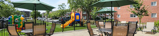 an outdoor patio with chairs and umbrellas and a playground