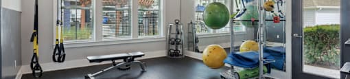 A gym with a bench, weights, and exercise equipment.