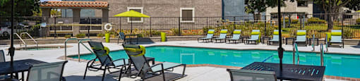 A pool area with chairs and umbrellas.