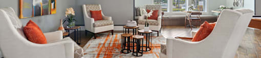 A living room with a white couch and orange pillow.