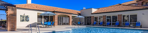 A large swimming pool in front of a building with a blue sky in the background.