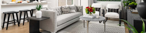 A modern living room with a grey sofa, a grey coffee table, and a white ceiling fan.