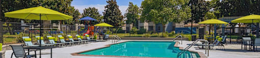 A pool with a hot tub and sun loungers.