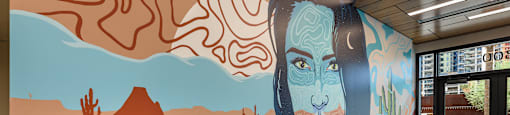 A desert scene with a woman's face is painted on a wall.