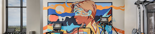 A gym with treadmills and a colorful mural on the wall.