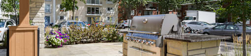 a gas grill on the side of a patio with trees