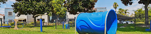A blue tube-shaped playground slide in a grassy area.