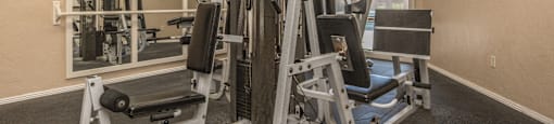 A well-equipped gym with a mirror and a variety of machines.