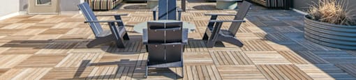 A patio with a table and chairs is set up on a wooden deck.