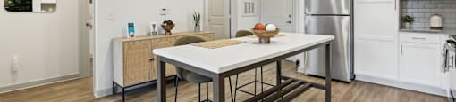 A modern kitchen with a wooden table and stainless steel appliances.