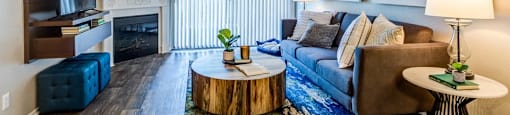 A living room with a blue couch, a wooden coffee table, and a large painting on the wall.