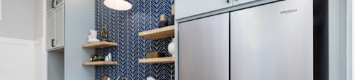 A modern kitchen with a large stainless steel refrigerator and wooden shelves.
