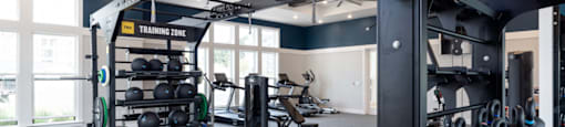 A gym with a variety of equipment including kettlebells and weightlifting racks.
