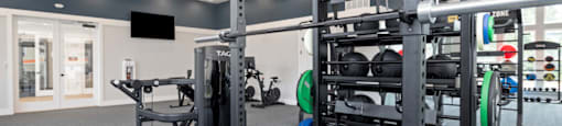 A gym with a variety of equipment including a squat rack, bench, and weights.