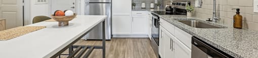 A kitchen with white cabinets and a wooden table.
