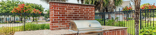 a brick outdoor kitchen with a grill and palm trees