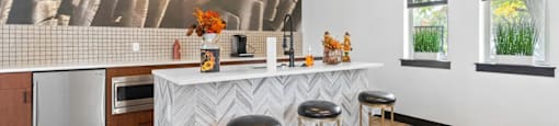 A kitchen with a white counter and bar stools.