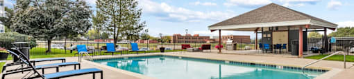 A swimming pool with a bench and a pavilion.