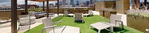 A rooftop patio with white furniture and a view of the city skyline.