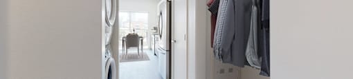 A hallway with a washing machine and a chair.