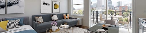 A modern living room with a grey couch, a coffee table, and a large window overlooking the city.