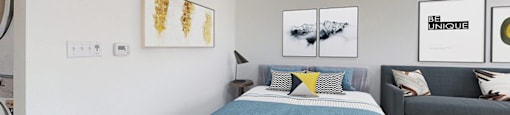 A bedroom with a bed, a couch, and pictures on the wall.