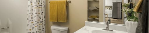 A bathroom with a toilet, sink, and mirror.