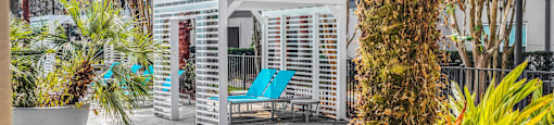 a patio with a blue chair and a white structure