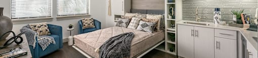 A bedroom with a bed, a chair, and a fan.