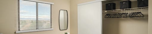 A bedroom with a bed, a mirror, and a closet with shelves.