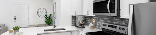 A modern kitchen with white cabinets and stainless steel appliances.